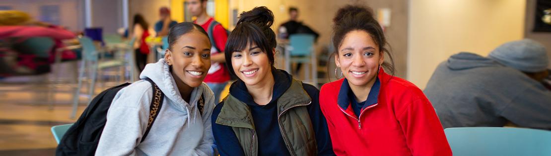 three students sit in a Pima Campus student lounge smiling 